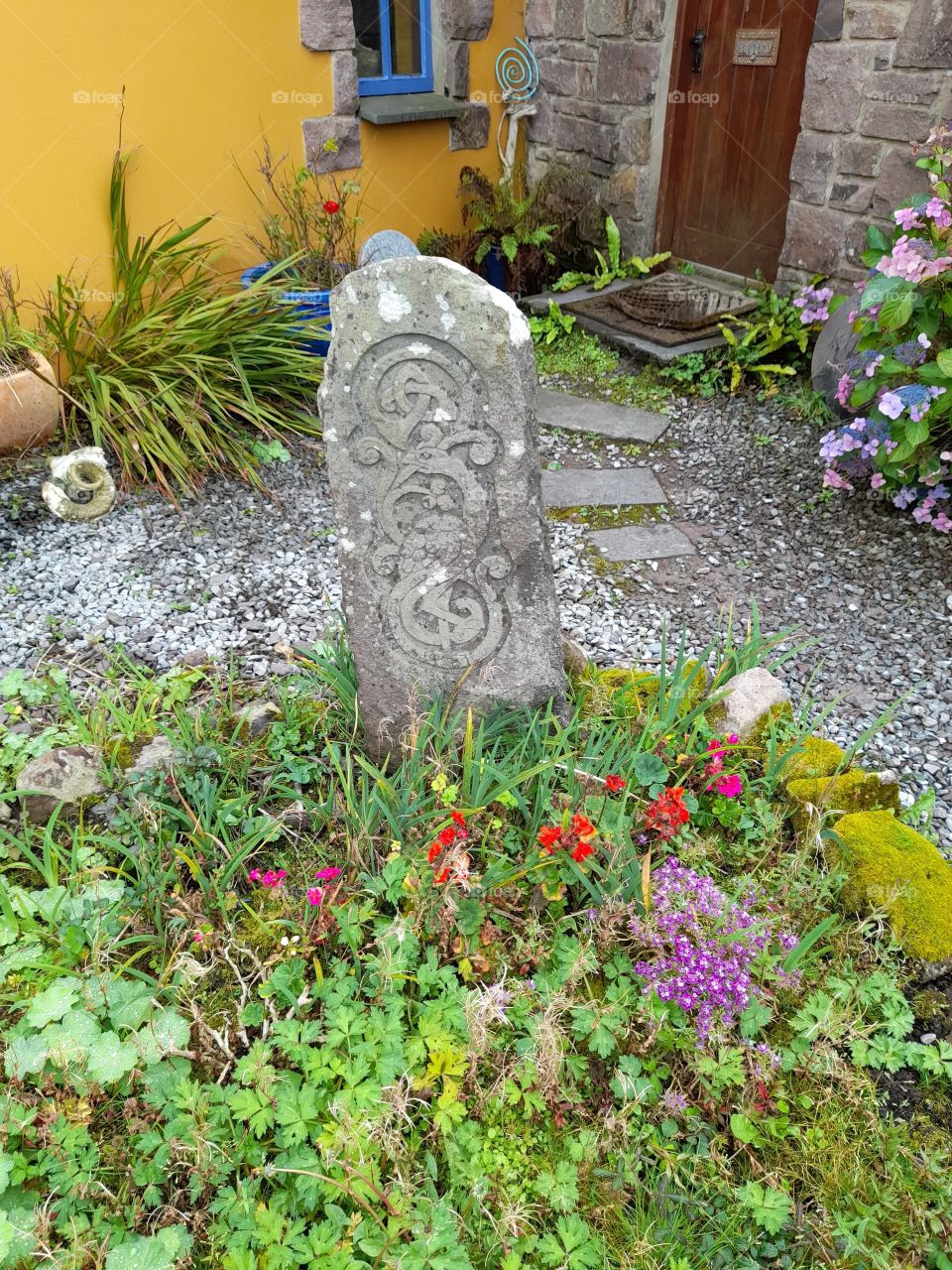 Standing stone Ireland with Celtic knots, garden and flowers