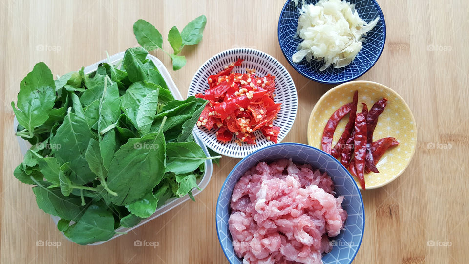 Raw main ingredients forThai famous spicy menu : Stir-fried minced pork with basil which are Basil leaves, minced pork, dry red Chilli, choped garlics, fresh pounded red chilli. - top view