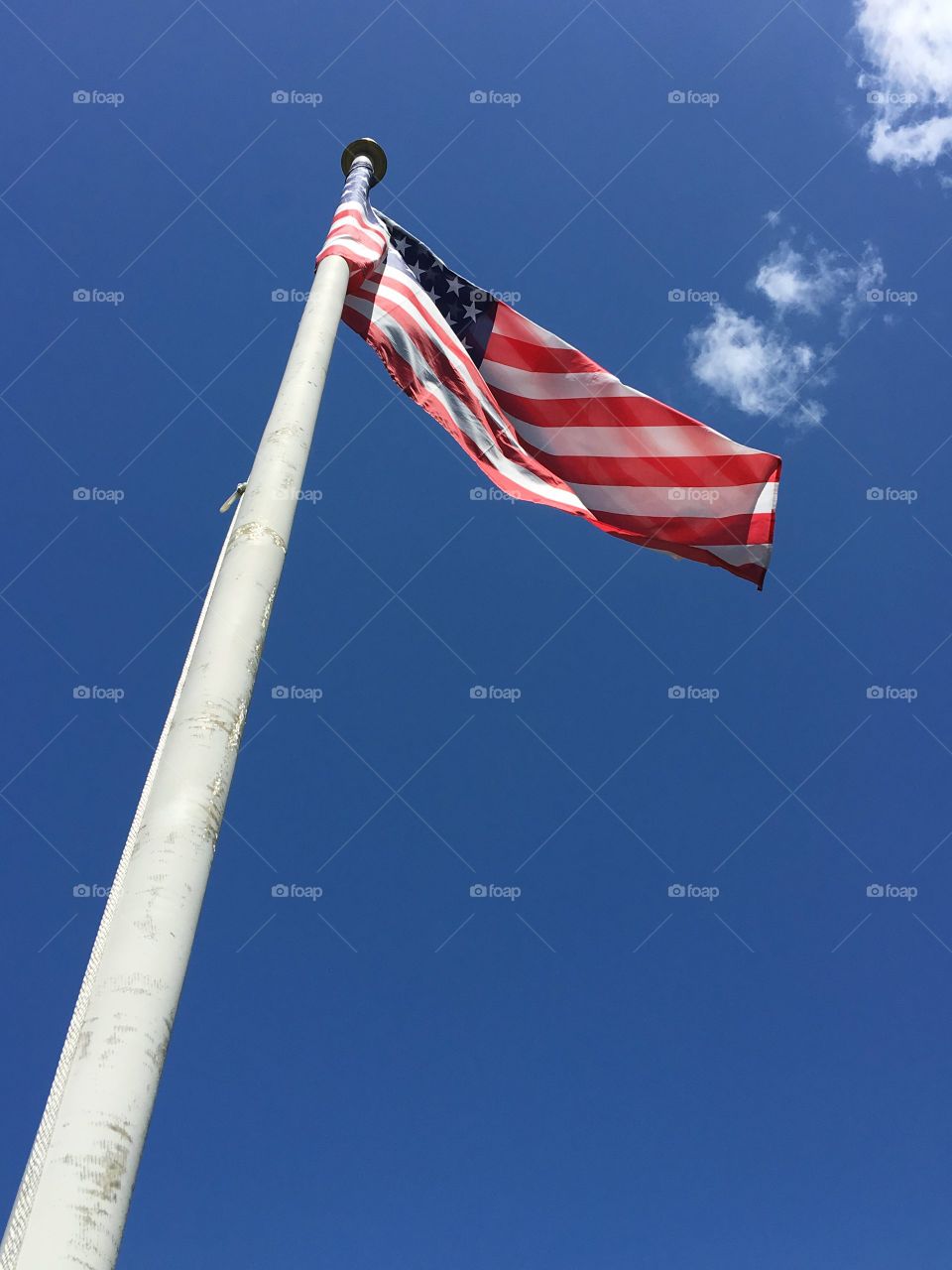 Looking up flagpole to the American Flag blowing in the wind against a beautiful blue sky 🇺🇸