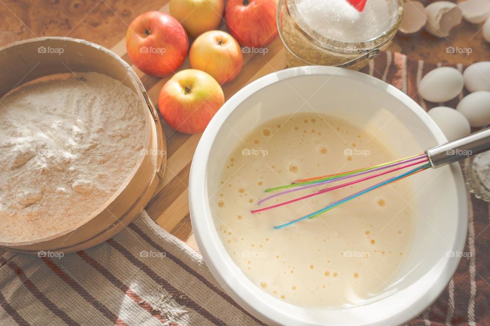 Making an apple pie dough using eggs, flour, sugar and apples.