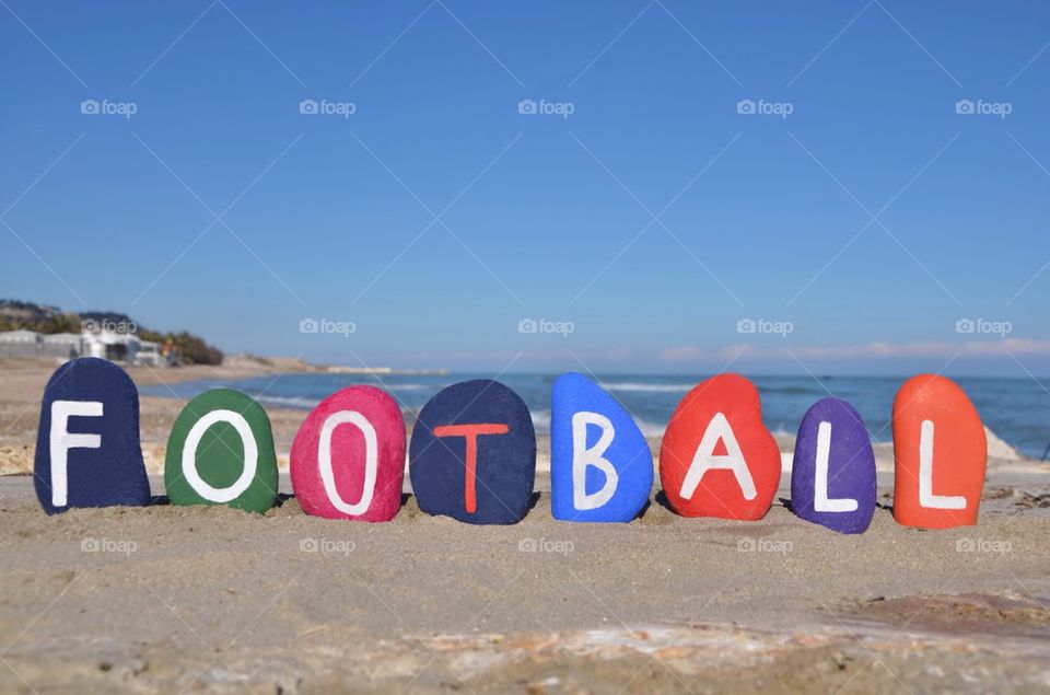 Football, colourful stones composition on the sand