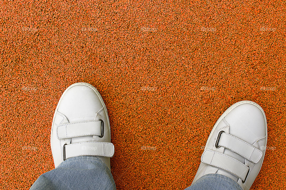 Low section of person standing on orange painted road