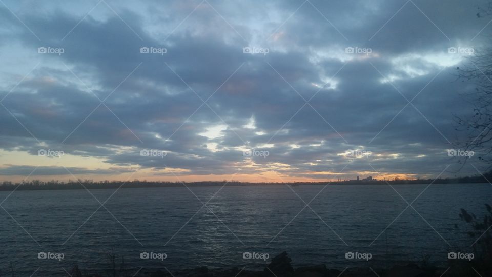 Scenic view of lake against cloudy sky at sunset