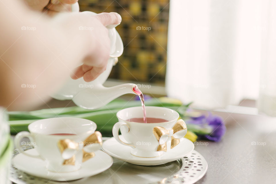 Person pouring tea in tea cup