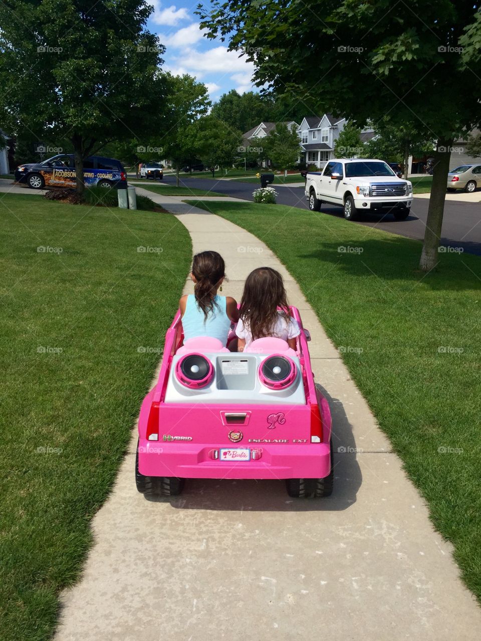 Little girls from behind riding on pink power wheel car