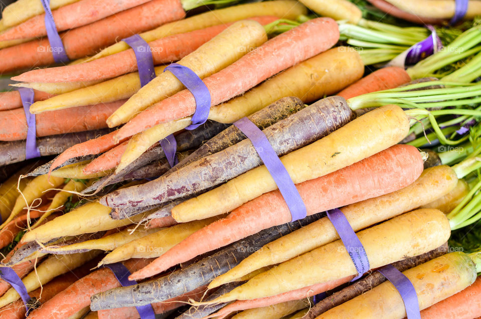 Close-up image of bundles of orange and multicolored carrots at a farmers market