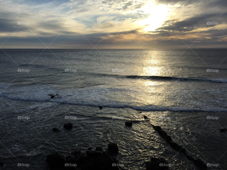 Beach before sunset clouds and waves reflecting light