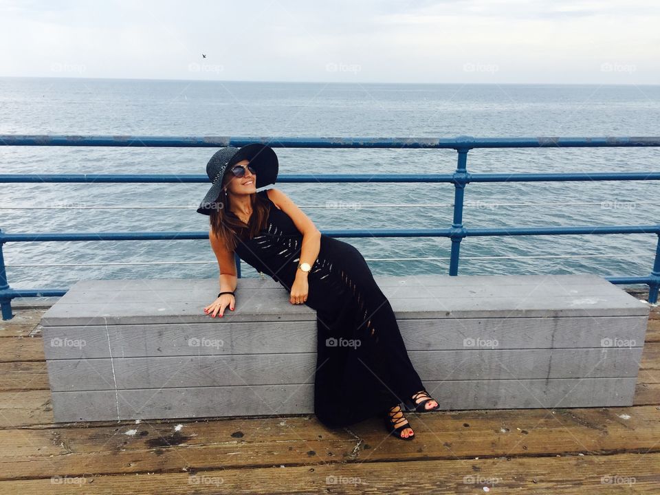 Young woman sitting on bench at sea side