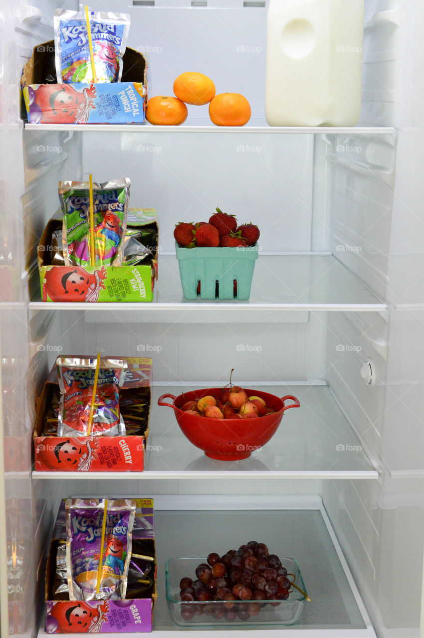 Drink pouch cases of assorted flavors shown in an open refrigerator with fruit