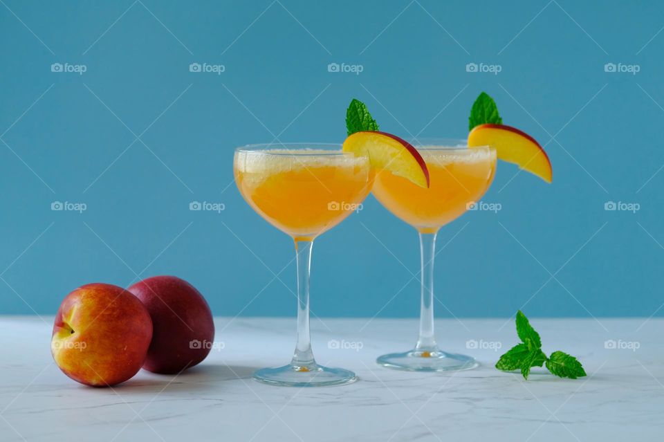 Close-up of peach cocktail drinks against blue background.