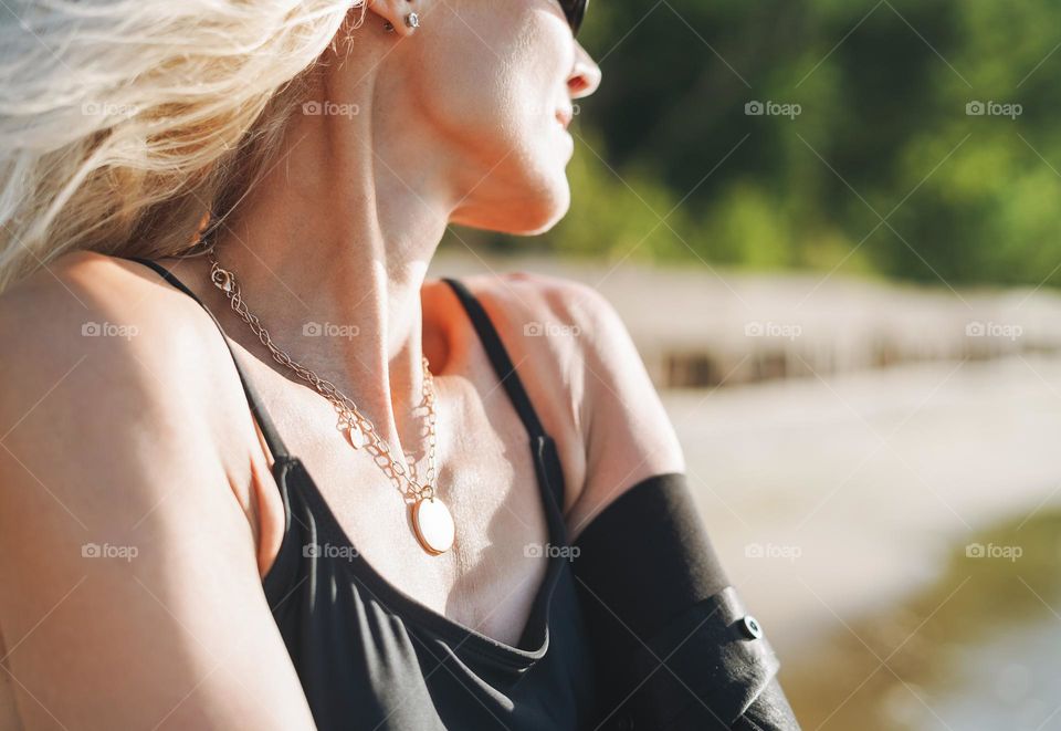 Young woman with beautiful jewellery necklace on sea background 