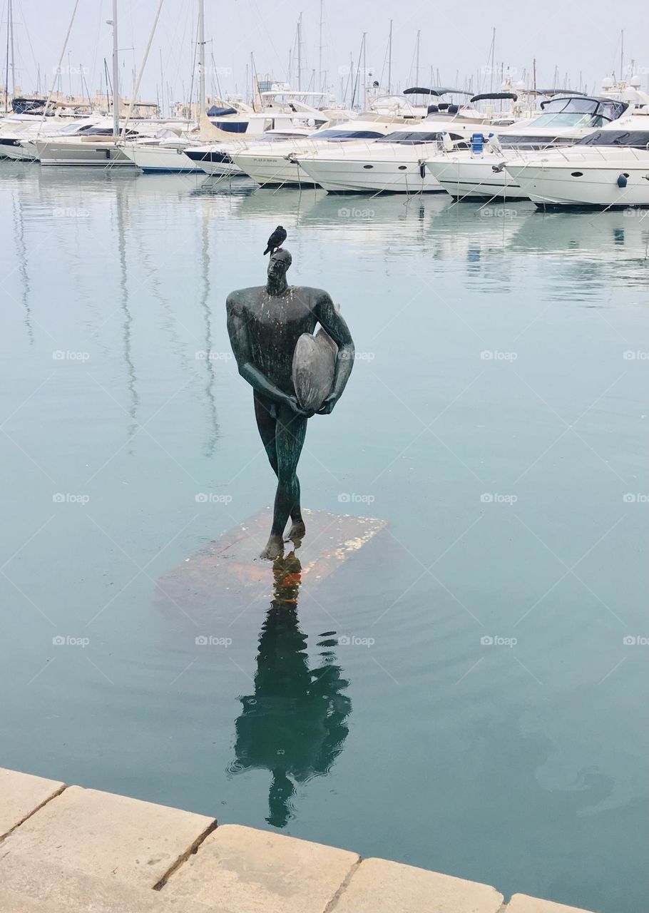 Pigeon sitting on Icarus statue