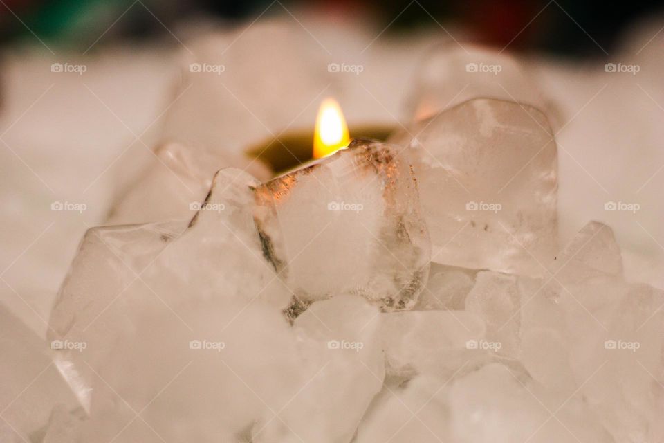 What’s fire doing in the ice?!? A green candle burning in a pile of ice on a mirror on a multicoloured tablecloth.