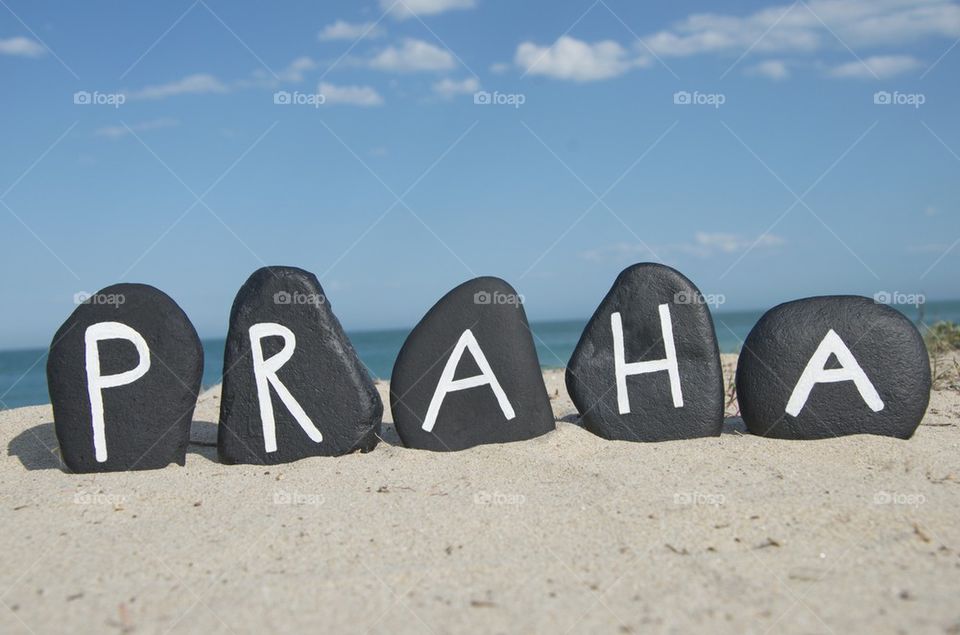 Praha on black stones over the sand