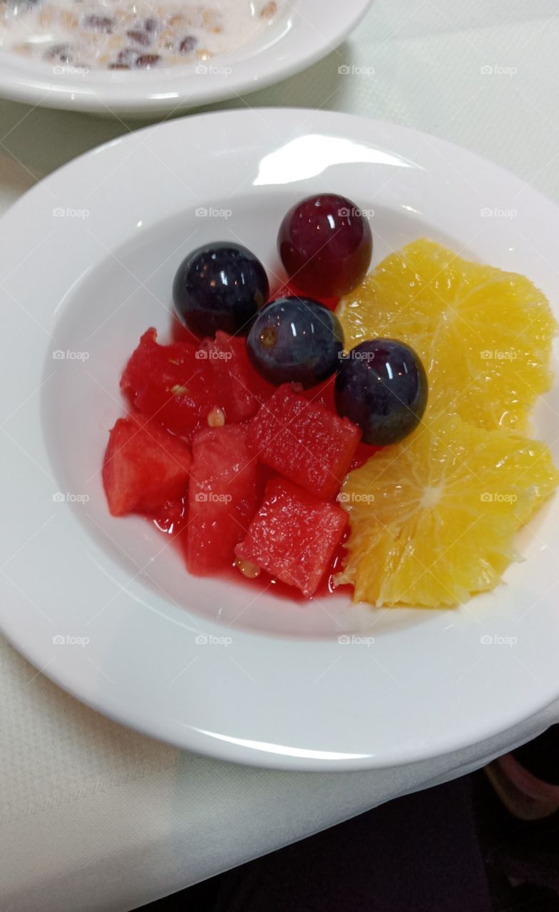 Fruit platter with dices of watermelons, juicy slices of oranges and some black grapes