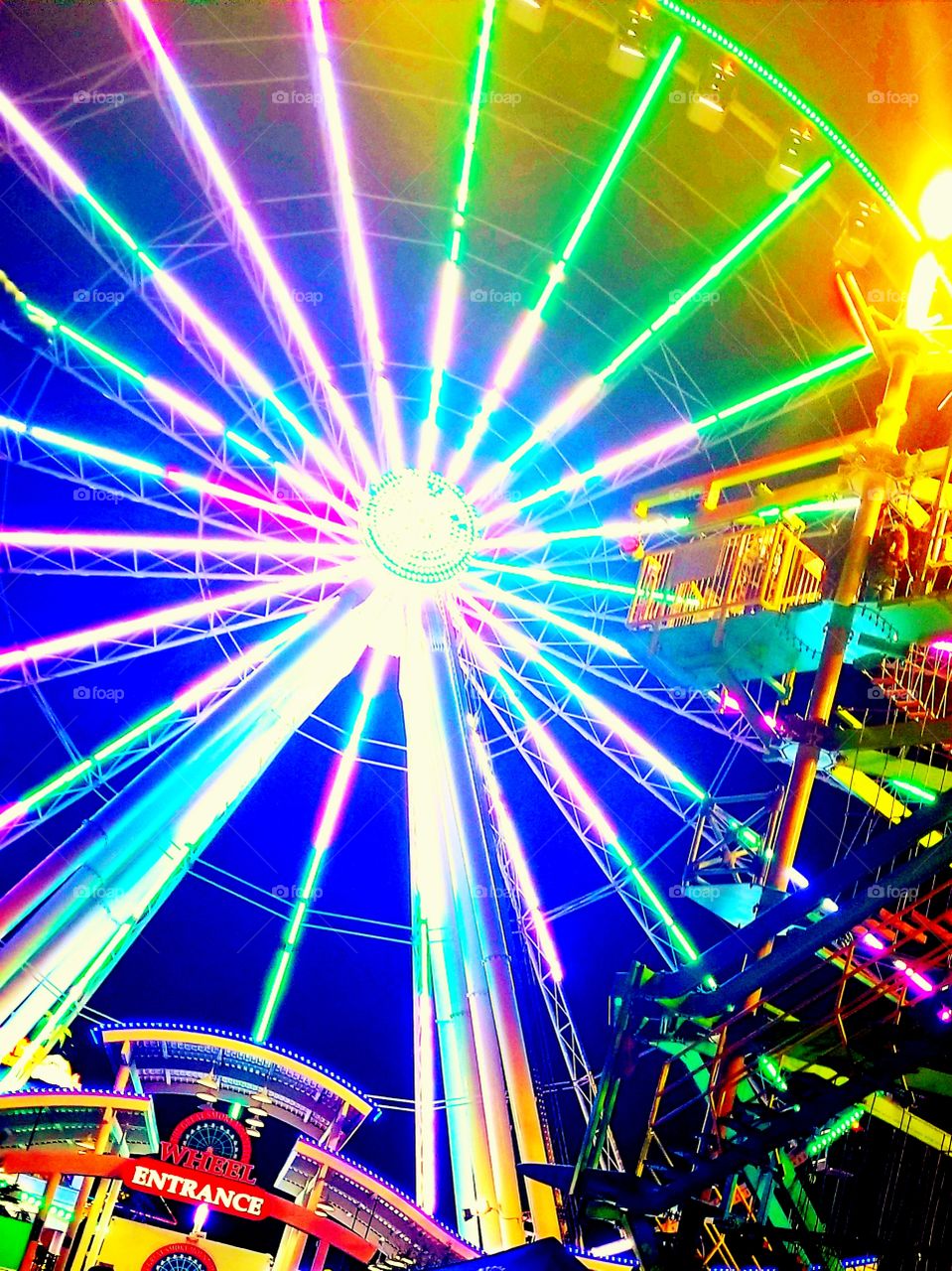 Lit up summer nights at the fair with the spokes of multicolored LED lights on the ferris wheel and fun vibe being sent.