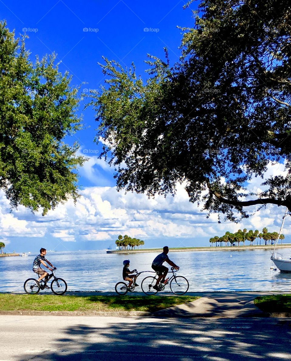 Bike riding, along the water, with child in tow. 