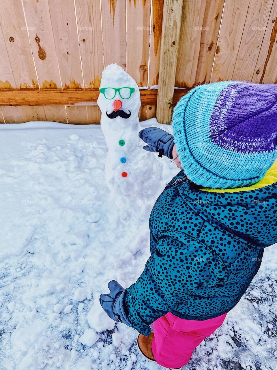 Icy art with children, toddler shows off snowman, toddler is excited about making a snowman, icy artistry in the backyard, having fun in the ice and snow 