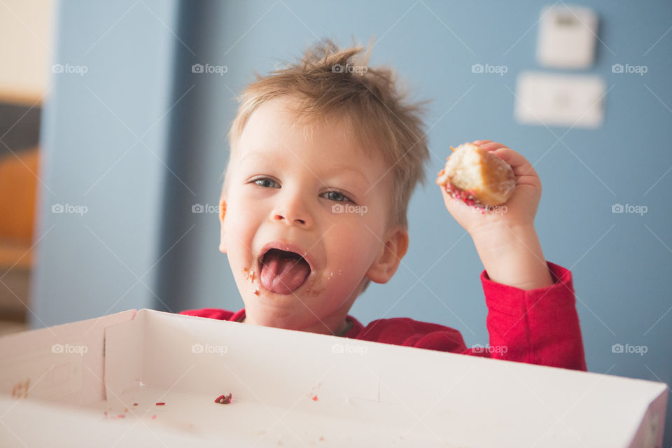 Toddler eating donuts and sticking tongue out 