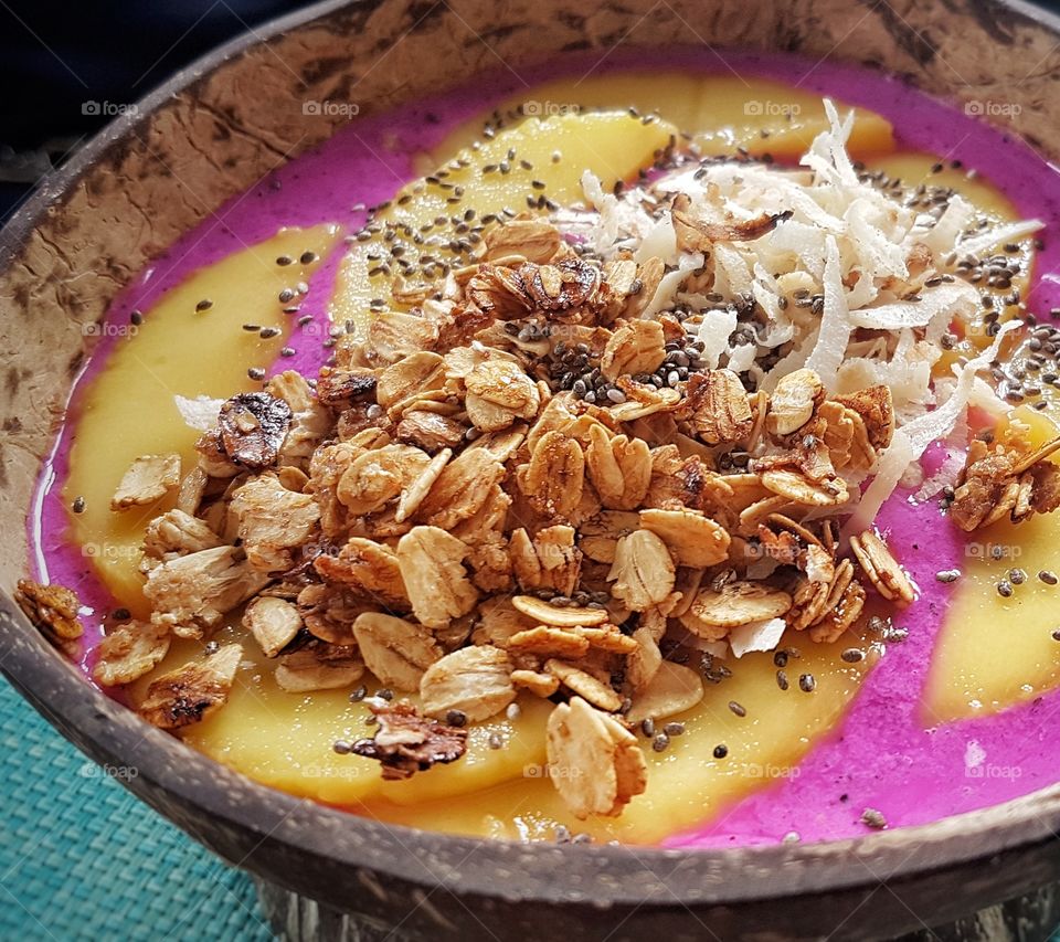 pink dragon fruit smoothie with mango slices and crispies