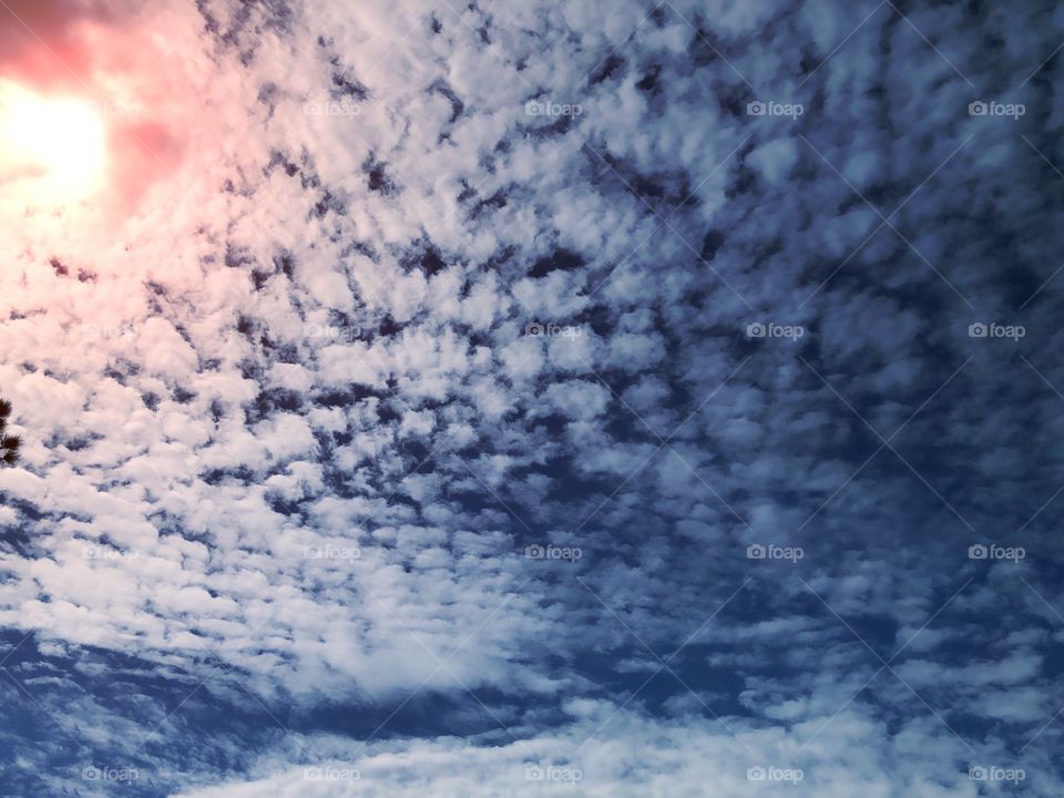 Sunset through white fluffy clouds.