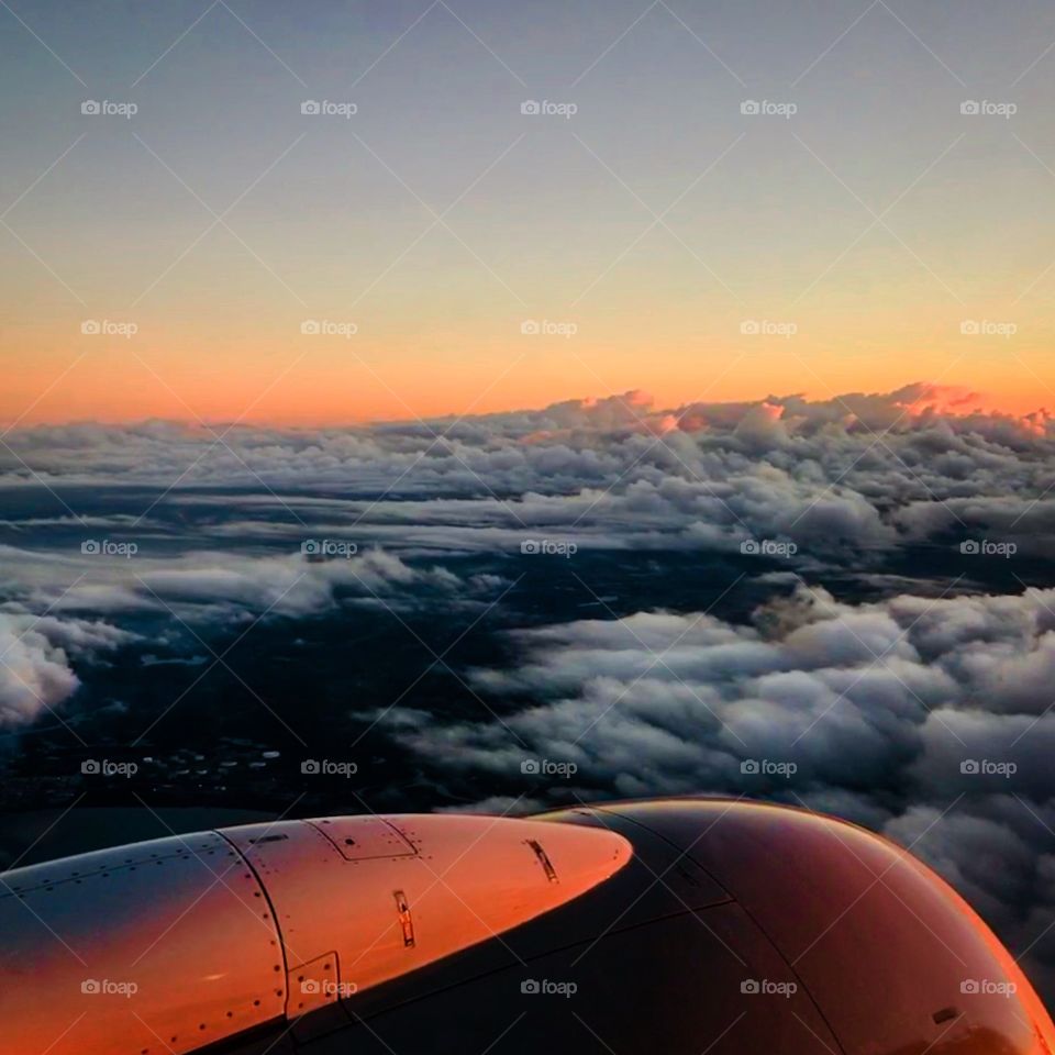 view from the window of an airplane flying over the clouds