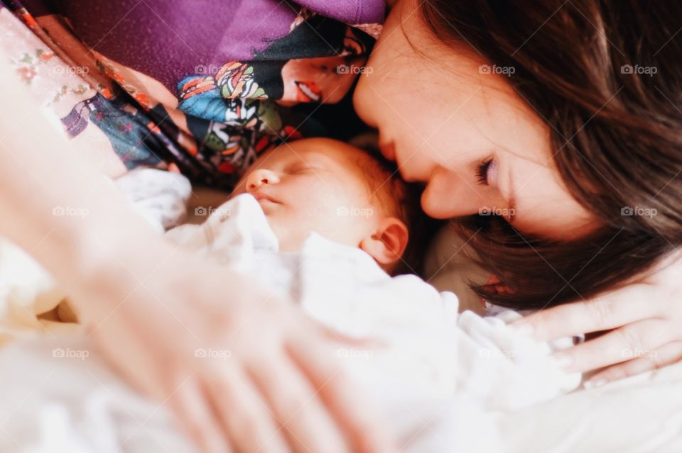 Mother with new born baby sleeping on bed