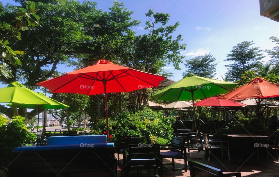 Green and red umbrellas are outdoors in the hotel, while I'm enjoying my hot coffee cup and listening to music.