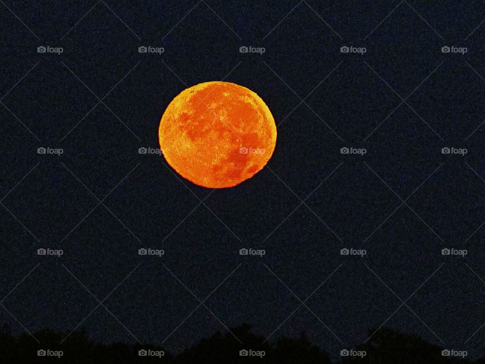 a orange colored moon in the midnight sky