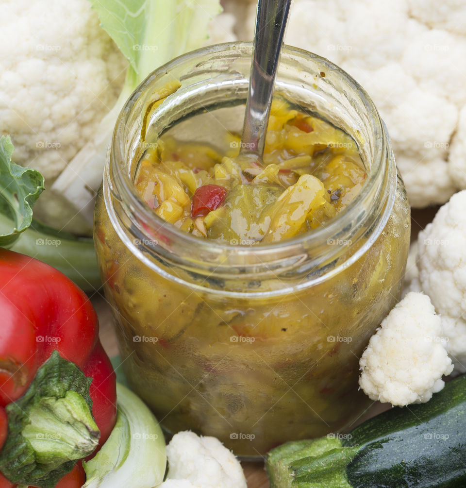 A close up view of a jar  of homemade sweet mustard pickles with capsicum and cauliflower .