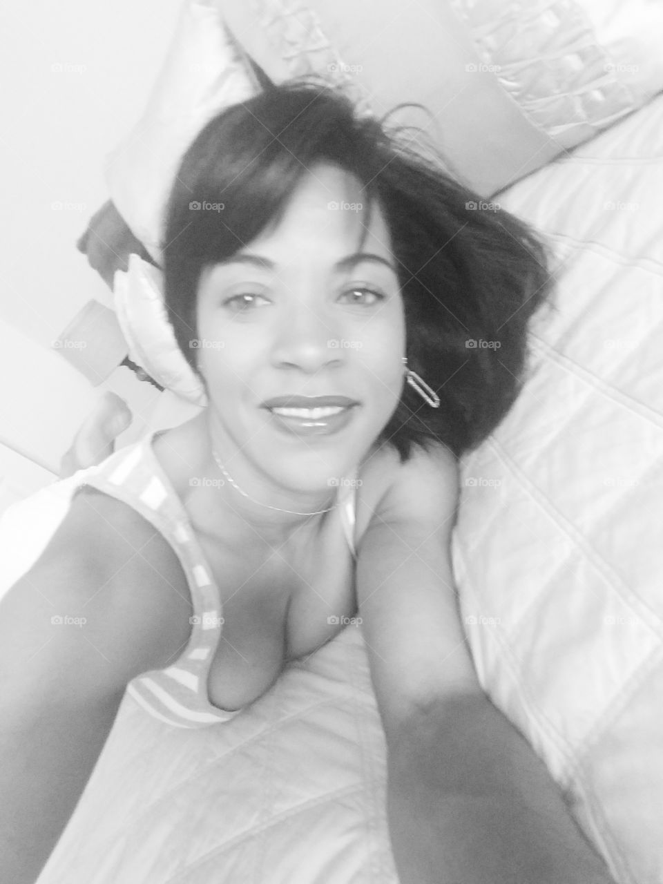 Woman lying on bed while taking selfie