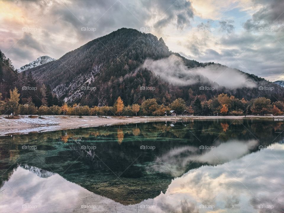 Scenic view of the beautiful reflection of the blue cloudy sky and Alps mountains in a lake in autumn trip in Slovenia