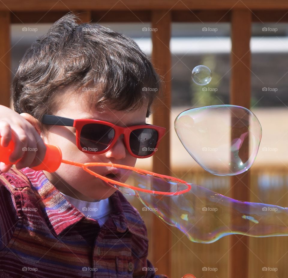 Little boy blowing big bubbles 