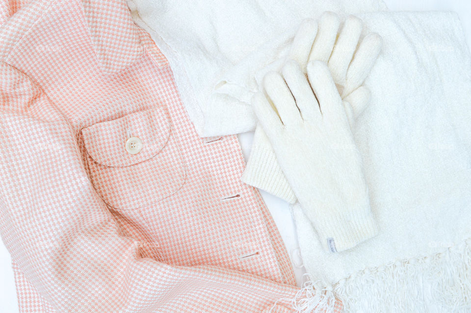 Flat lay of a coat with white gloves and scarf