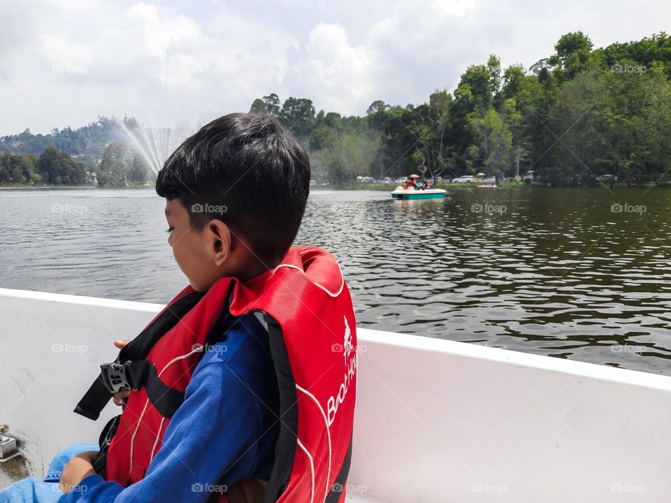 A kid in the boat during summer in the city