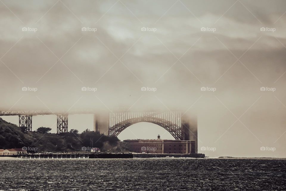 Sepia style image of the Golden Gate Bridge with the beautiful fog cascading right across the middle classic bridge within its art deco design welcoming people to the San Francisco Bay in California 