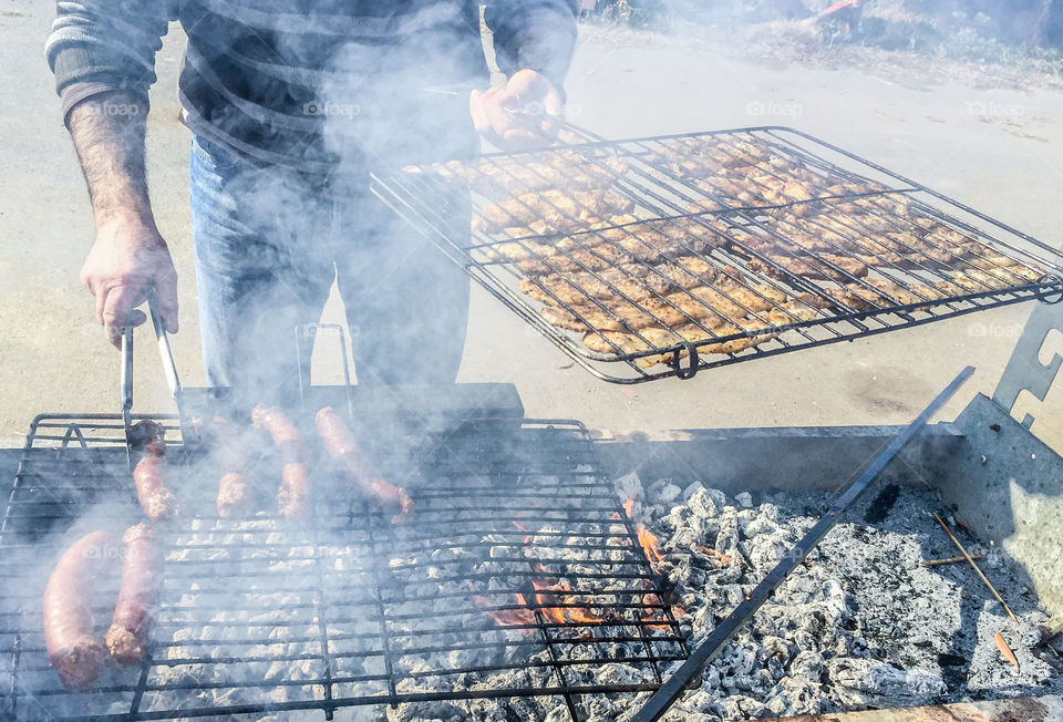 Man Roasting Sausages And Pork Meat on Barbecue Grill