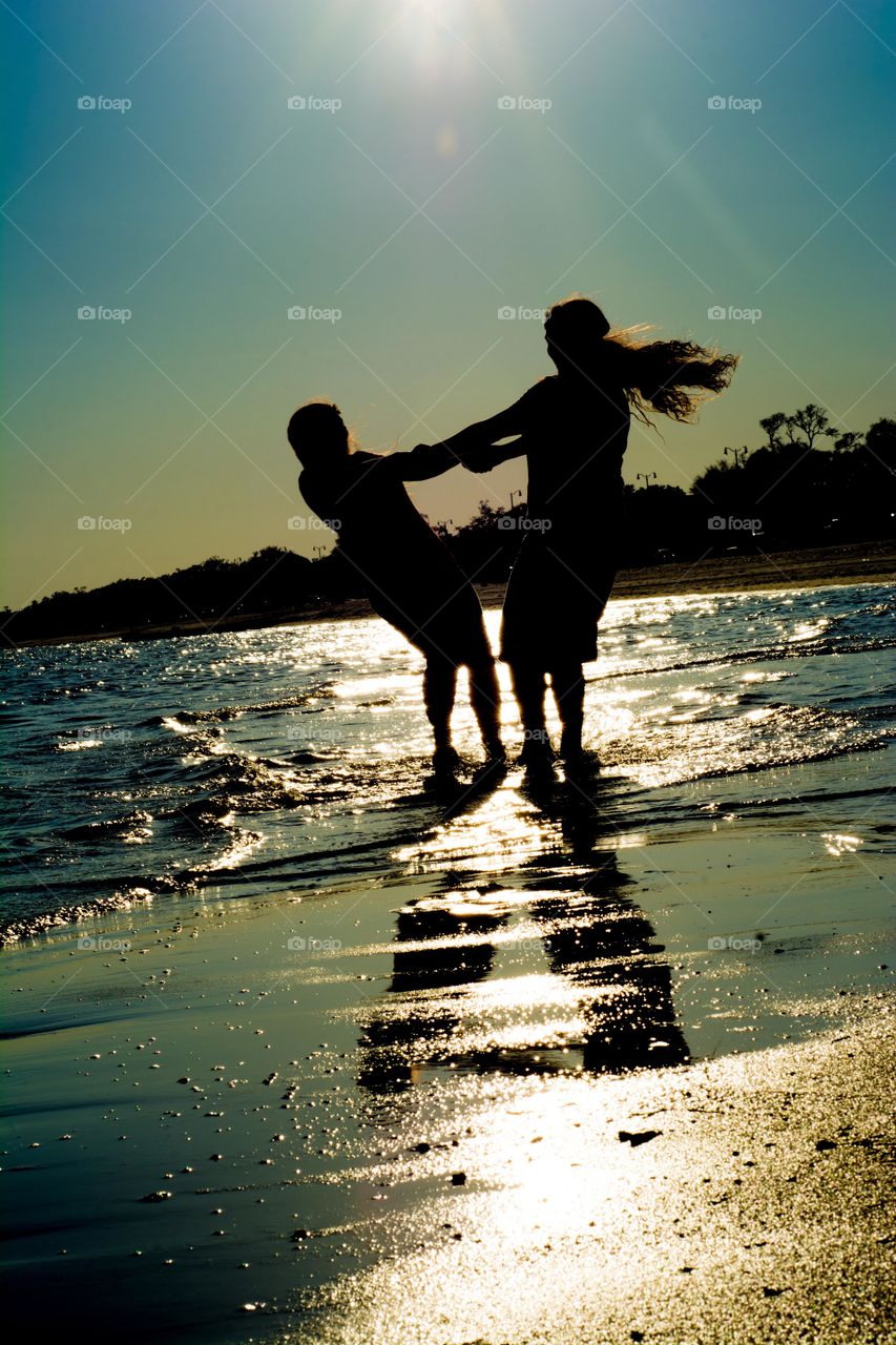 Silhouette of Two Girls Spinning in the Ocean Shore