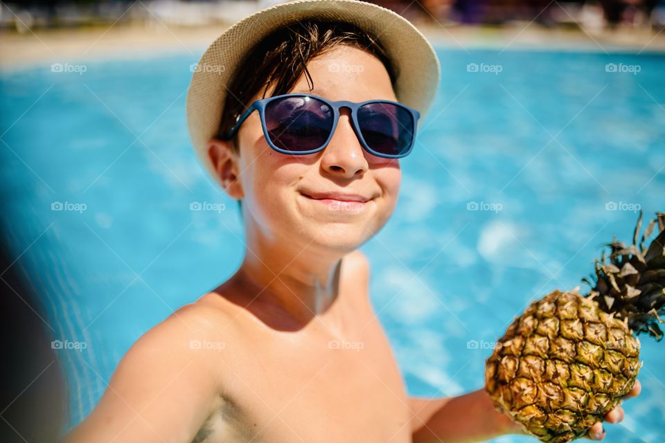 boy makes funny selfie in the pool