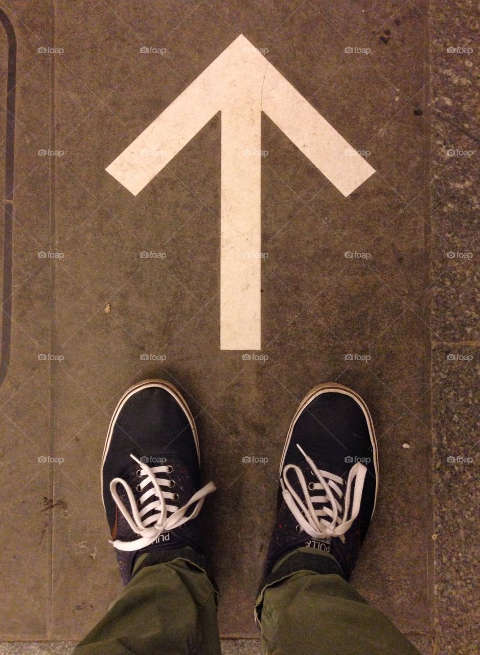 Blue shoes in front of the white arrow on the floor