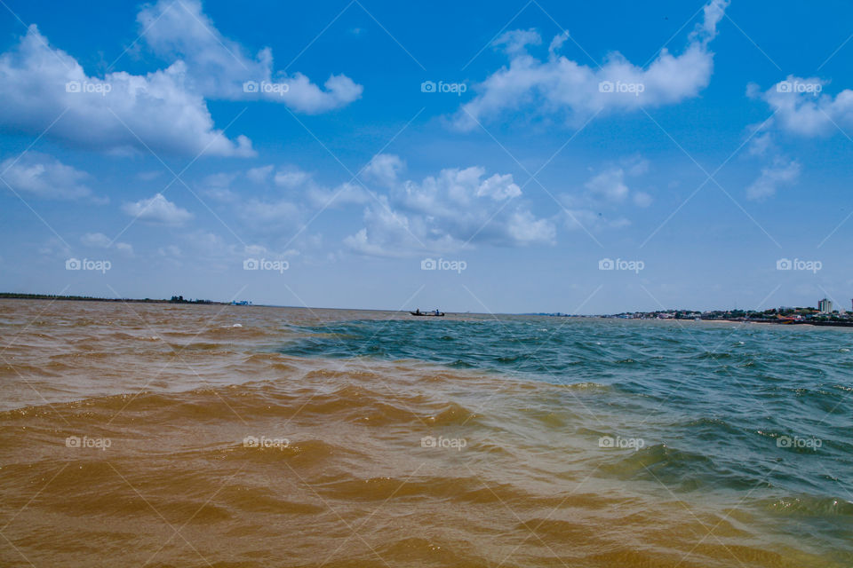 meeting of two different rivers in the Amazon. one is brown the amazona river and the blue os tapajos river. they meet for 20km and dont mix. blue sky