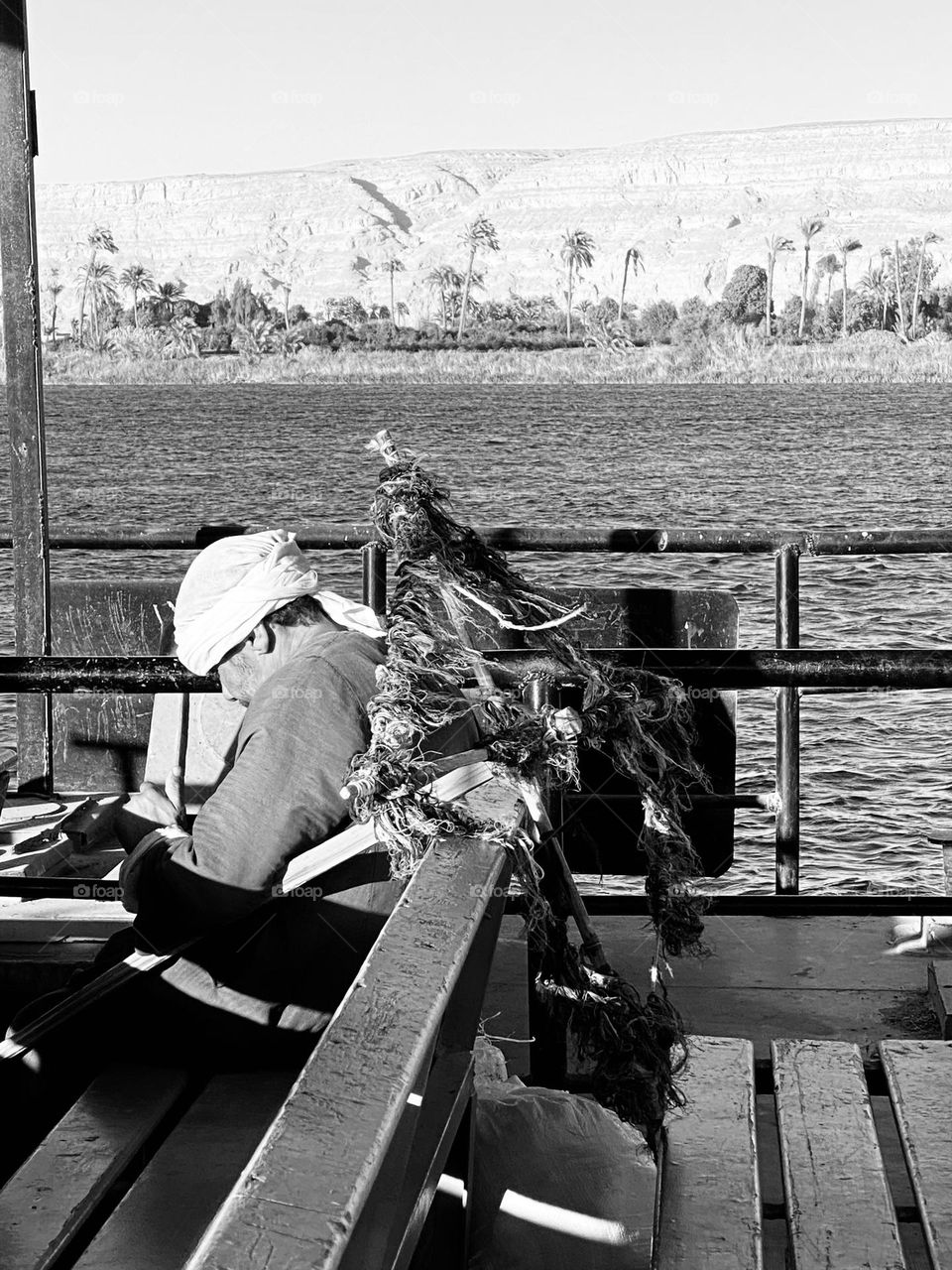 A man is using his mobile phone while taking a boat to the other side 