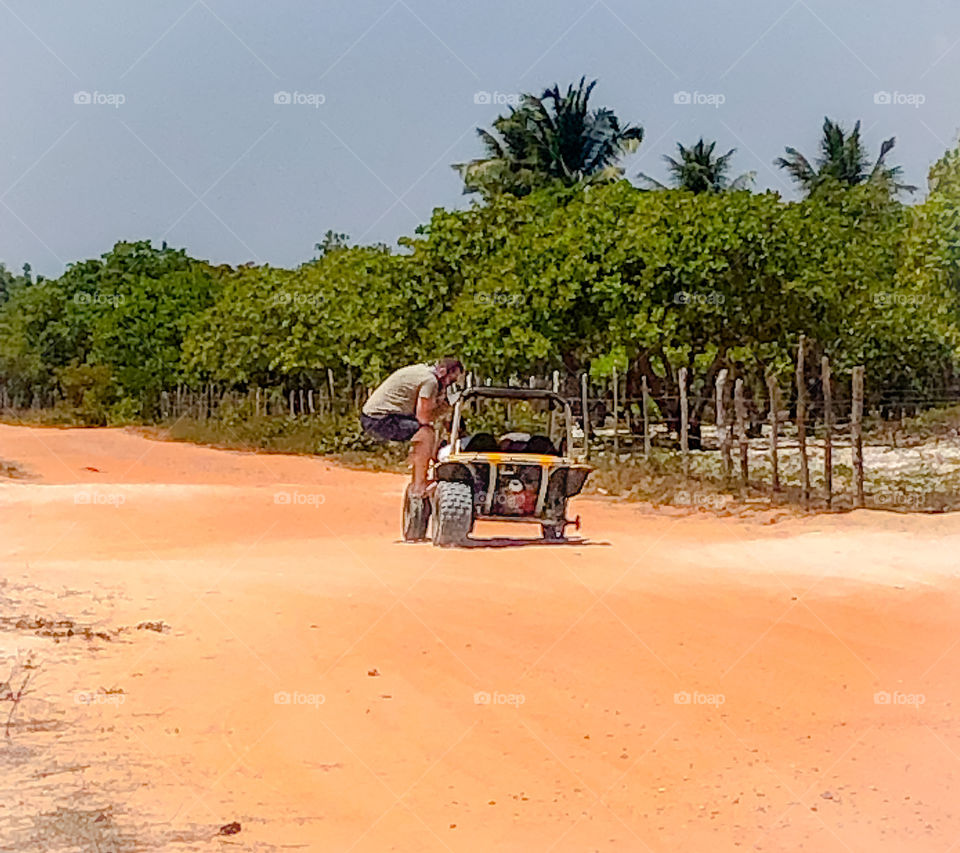 Man balancing missing wheel in a buggy 