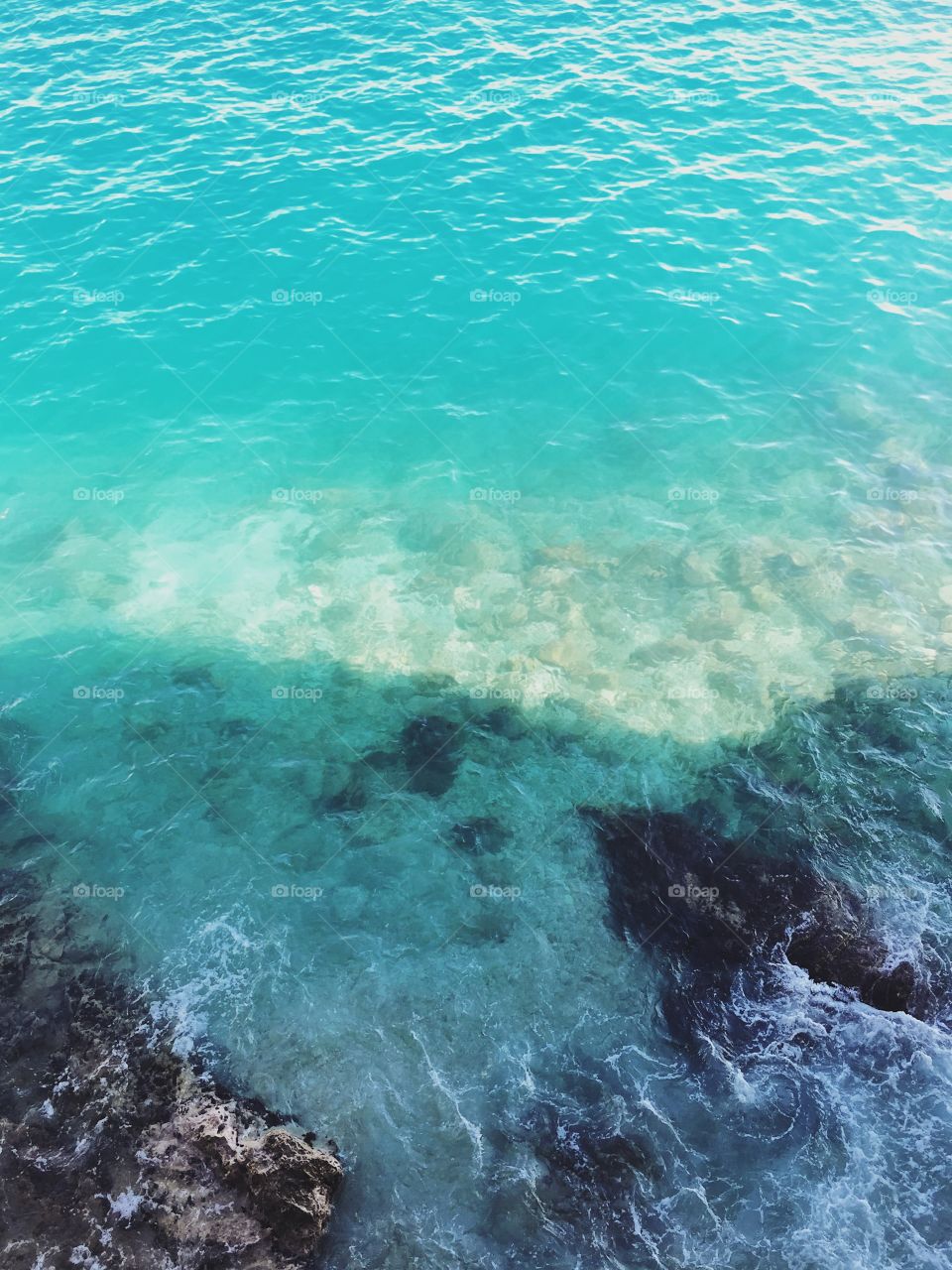 Top view over the Mediterranean Sea on a beautiful sunny afternoon. Sea waves against the rocks. Taken in Monaco, Monte Carlo.