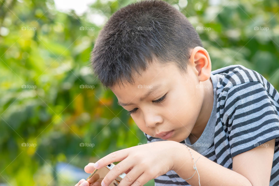 Portrait of Asian boys are playing mobile phones in park.