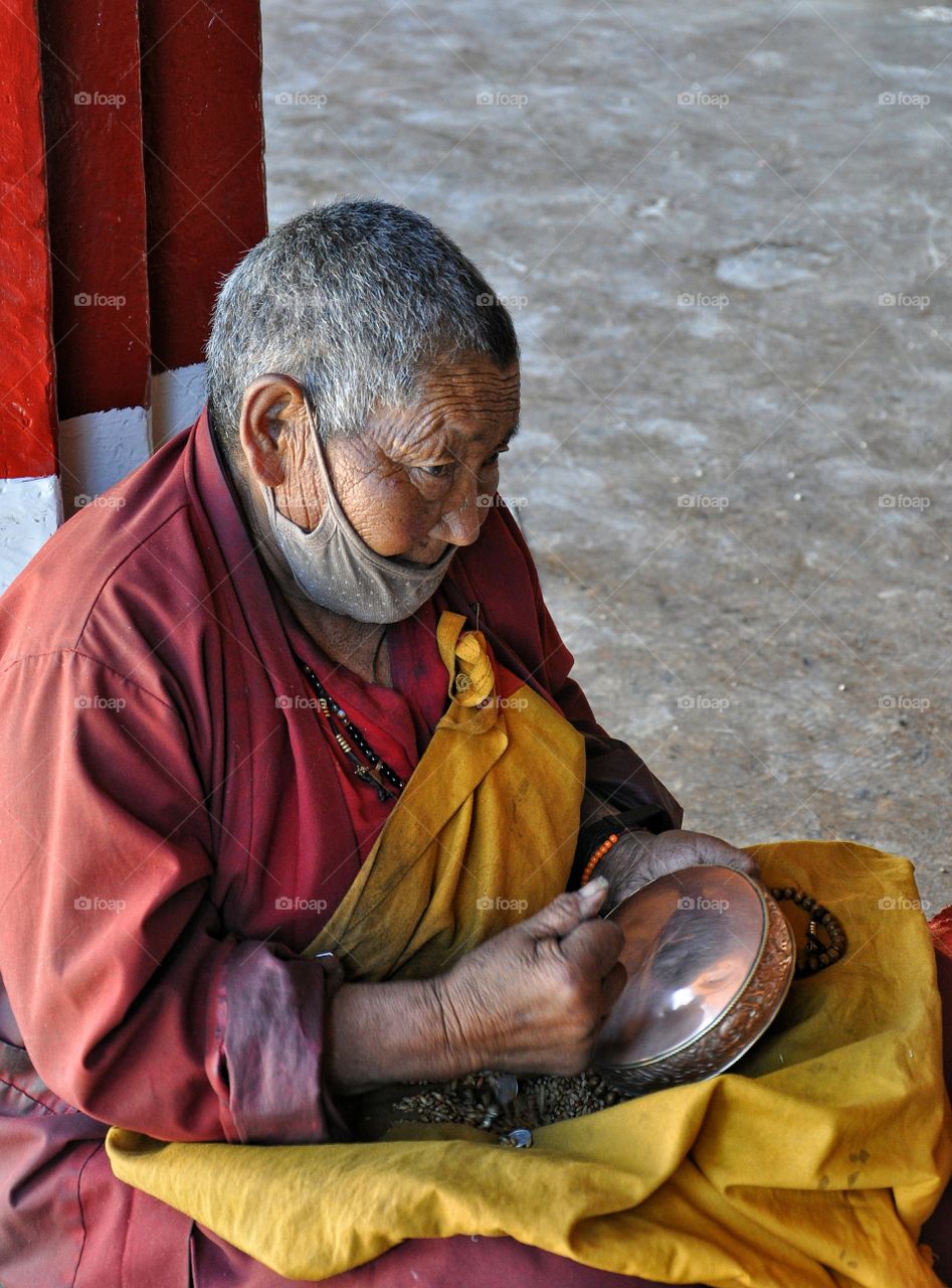 old woman sitting on the floor in buddhist monastery in lhasa