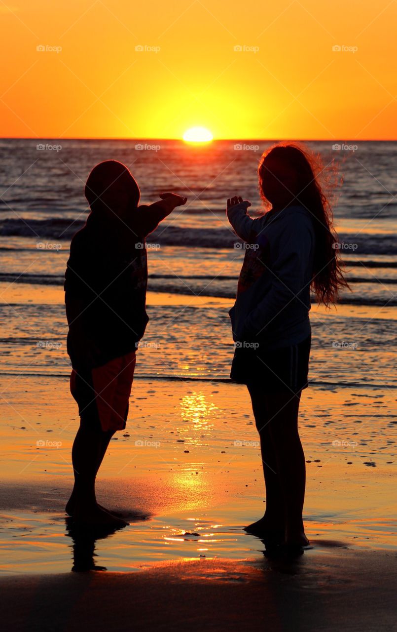 Silhouette of couple at beach during sunset with gesture