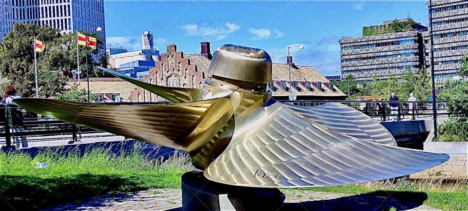 Modern art seems to be a big thing in “Malmö”, “Sweden” by the “Baltic Sea”, and ships; literally a big thing as we can see in the case of this oversized golden propeller put on the promenade. 2023. Hypnotic Productions