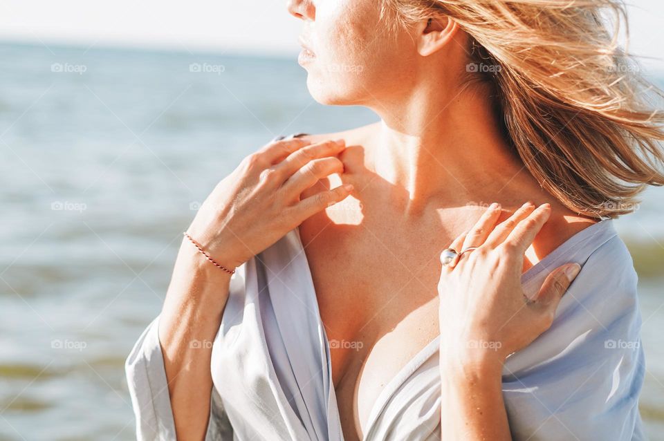 Young woman with beautiful jewellery rings on hands on sea background 