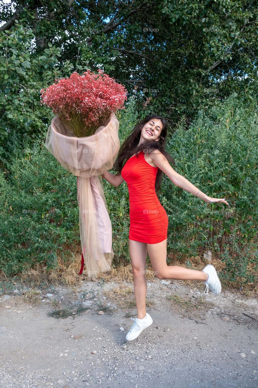 Beautiful Girl Dances with a Large Bouquet of Red Flowers